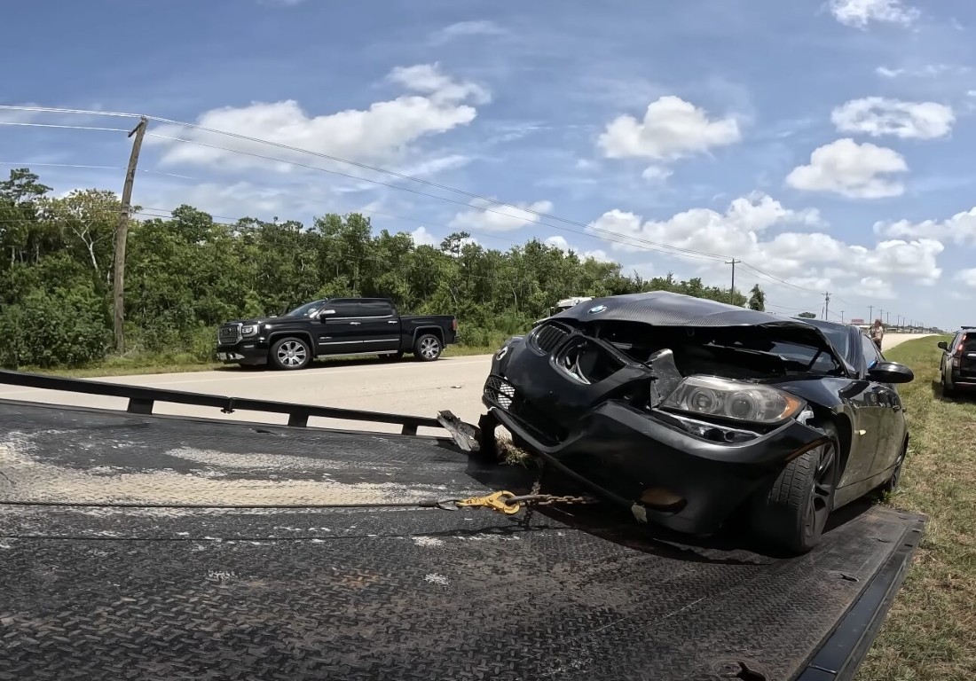 Accident recovery towing a wrecked BMW on a flatbed truck in Bay Shore, NY